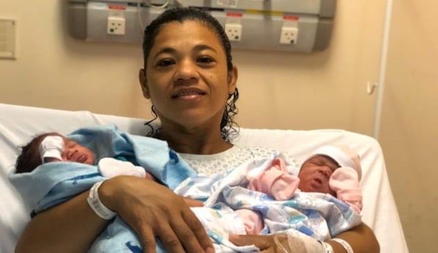 Mãe segurando recém-nascidos gêmeos