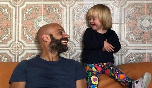 Homem sorrindo para criança loira em sofá