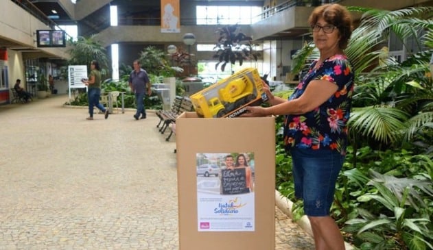 Senhora depositando caminhão de brinquedo em caixa de papelão