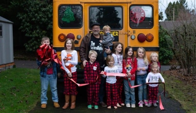 Avô com 10 netos crianças na frente de ônibus escolar amarelo