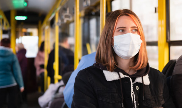 Menina com máscara anda de ônibus
