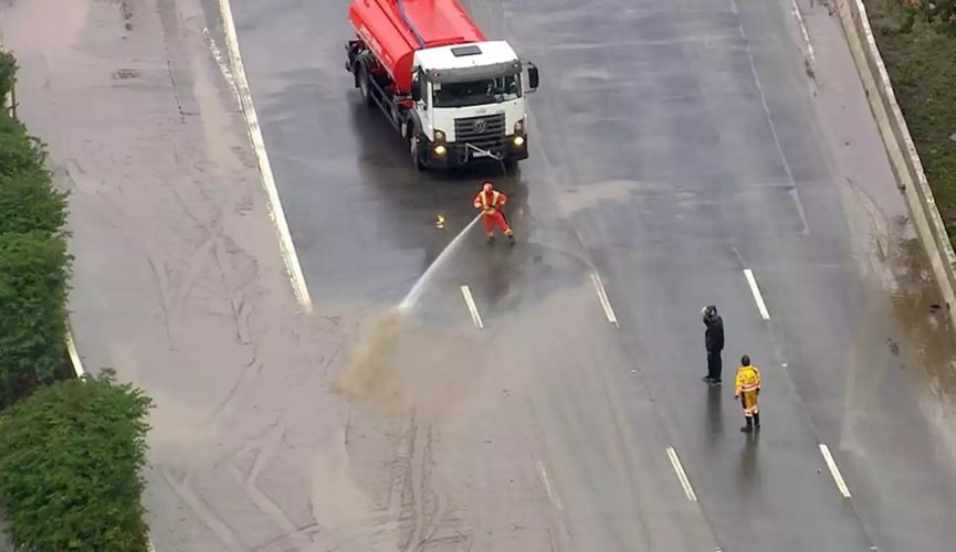Equipe de limpeza com caminhão tanque limpando via suja de água da enchente
