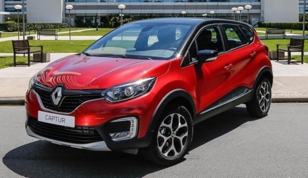 Carro Captur da Renault vermelho na frente de um prédio com gramado.