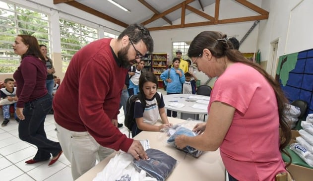 Foto de pais retirando uniforme escolar nas escolas