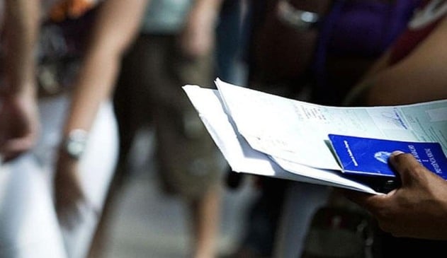 pessoa segurando currículo e carteira de trabalho