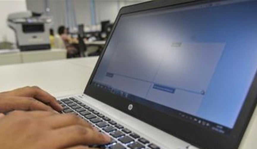 mão parda teclando em notebook cinza