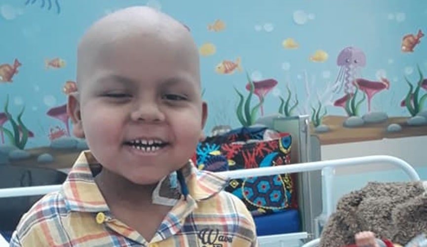 Criança careca sorrindo em quarto azul