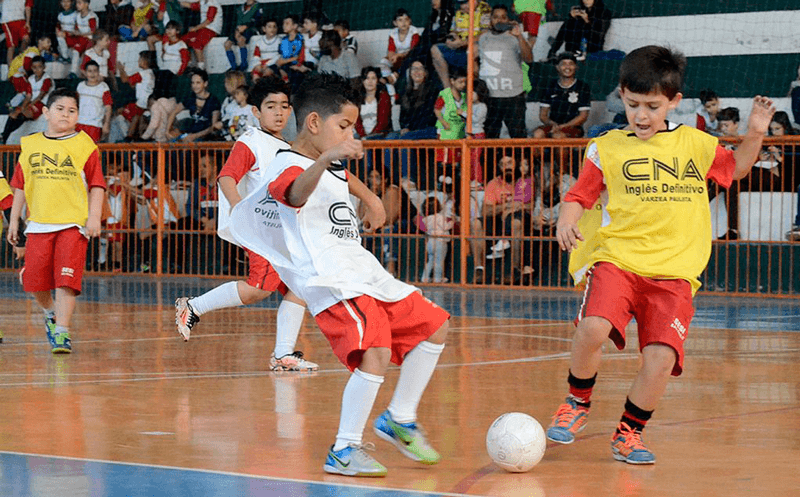 Crianças jogam futsal em quadra de centro esportivo