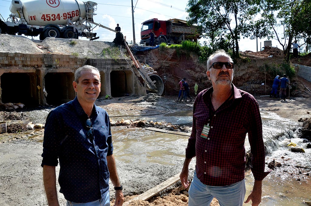 dois homens um do lado do outro observando uma obra de construção de um túnel