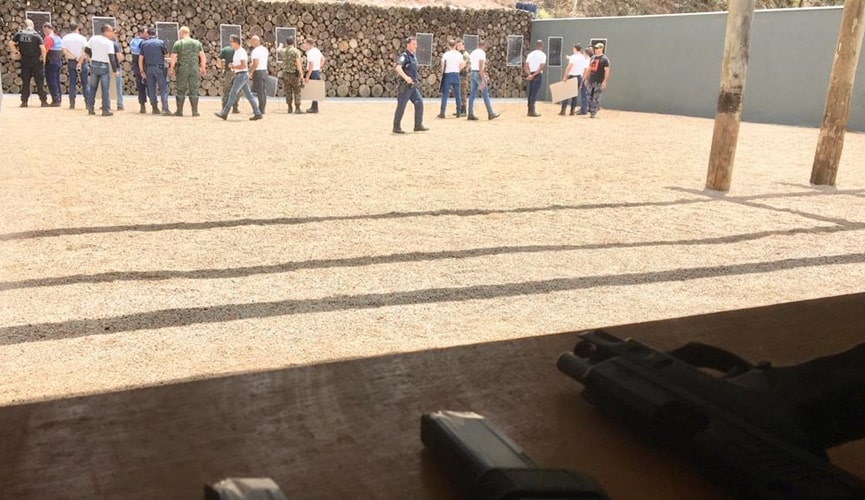 Estande de tiro com policiais, guardas e soldados do exércitos olhando os alvos acertados