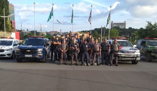 Policiais militares e guardas municipais ao lado de viaturas