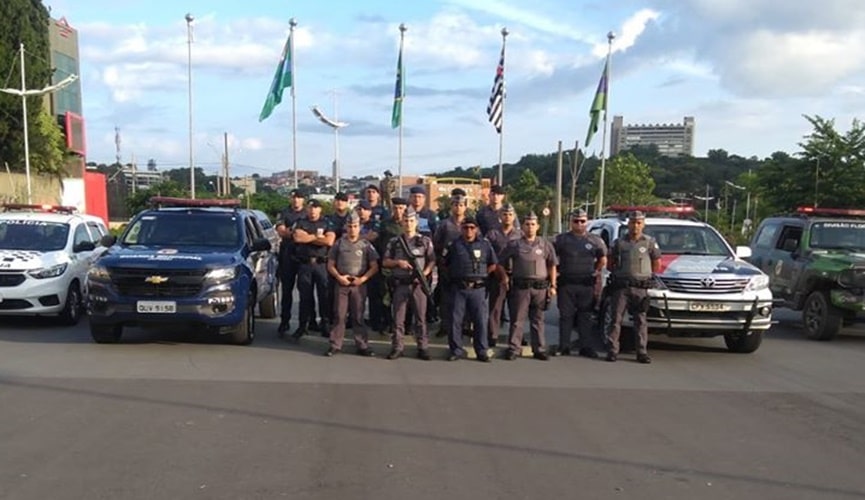 Policiais militares e guardas municipais ao lado de viaturas