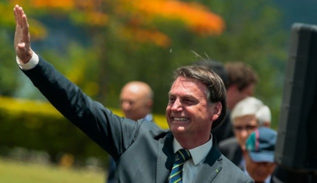 Jair Bolsonaro acenando em cima de um carro.