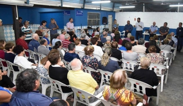 Luiz Fernando Machado ao lado de autoridades falando para público em salão fechado