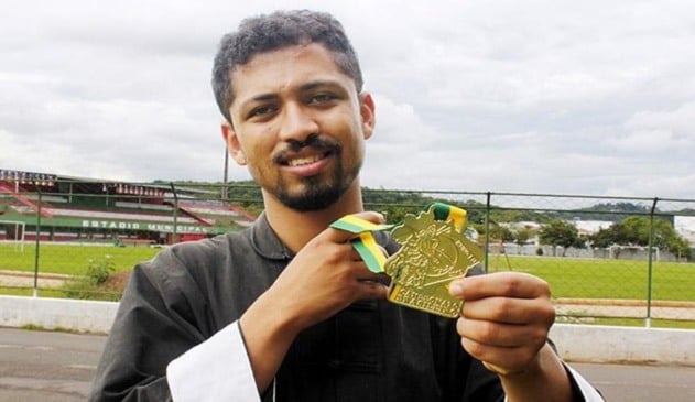 Rapaz negro segurando medalha de ouro em frente ao Ginásio de Esportes de Campo Limpo Paulista
