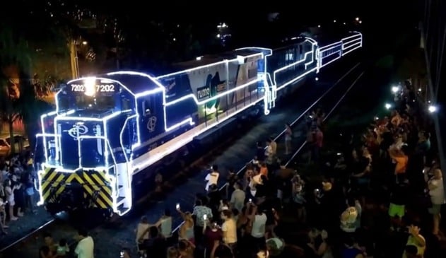 trem iluminado cercado por multidão de pessoas