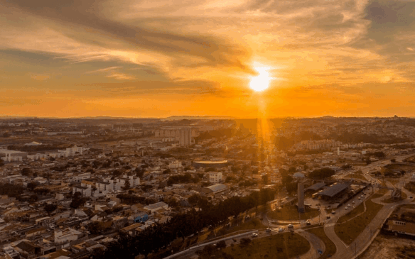 foto aérea de jundiaí com cidade abaixo e sol brilhando no céu com céu alaranjado