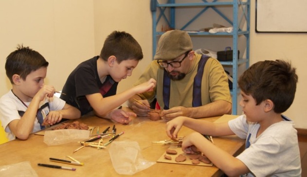 Homem ensinando crianças a fazer artesanato