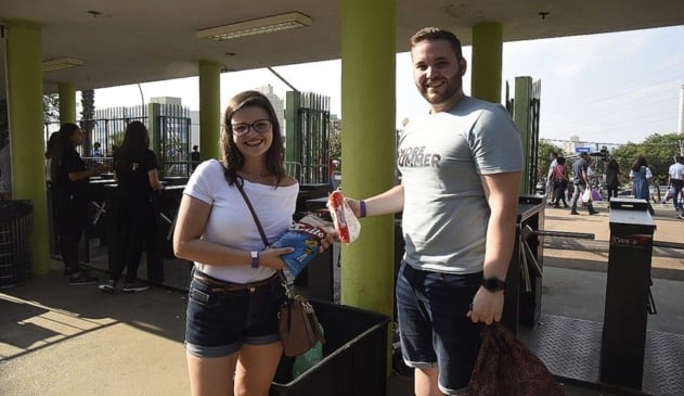 Casal depositando alimentos para doação em caixa