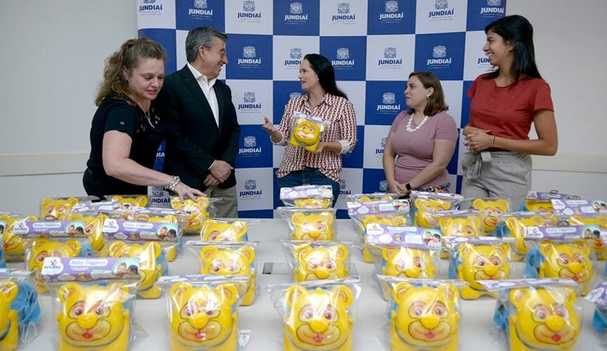 Mesa de brinquedos amarelos na frente de grupo de pessoas formados por quatro mulheres e um homem