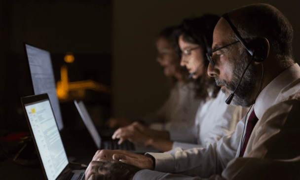 Trabalhadores usam headphones em ambiente a meia luz