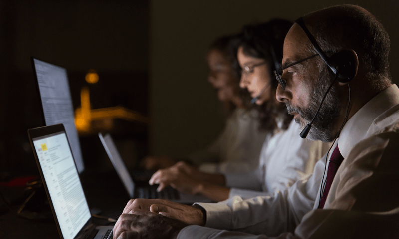 Trabalhadores usam headphones em ambiente a meia luz