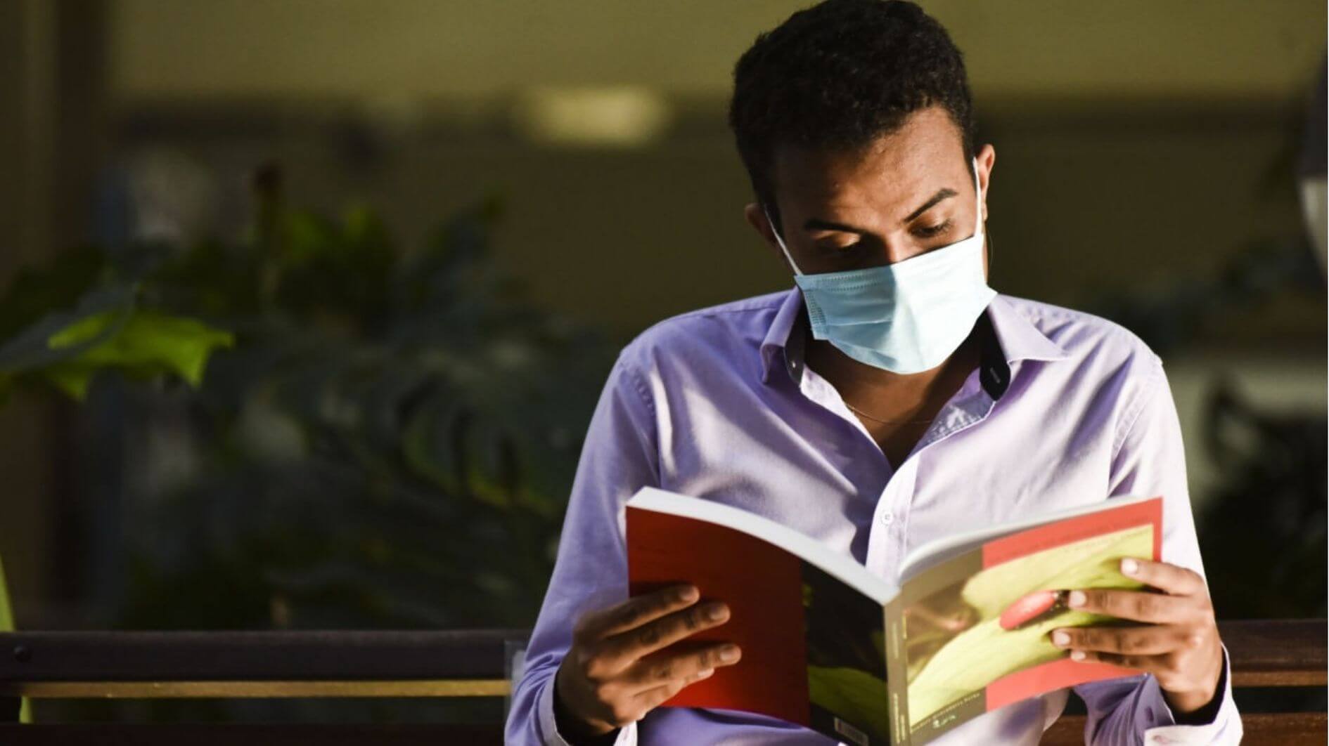 Homem usando máscara lendo um livro