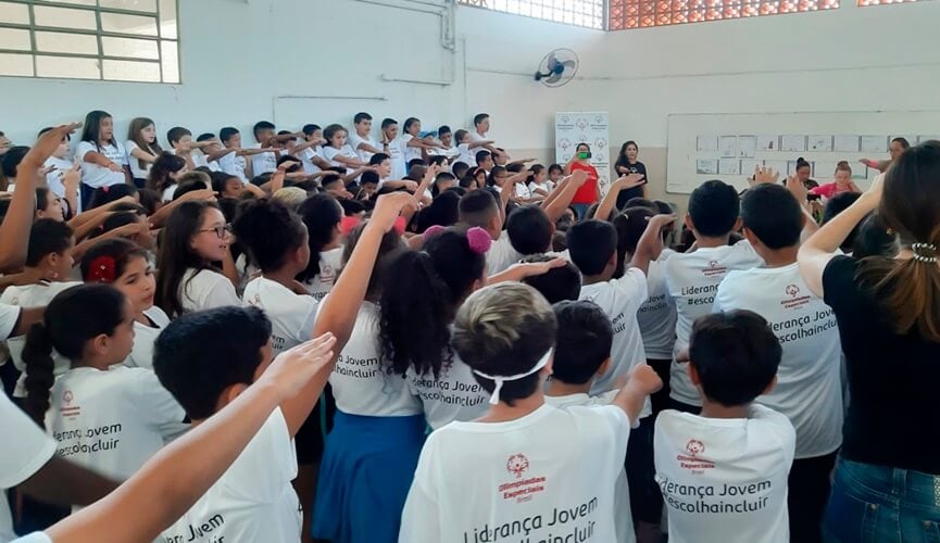 Crianças recebendo medalhas em pátio de escola
