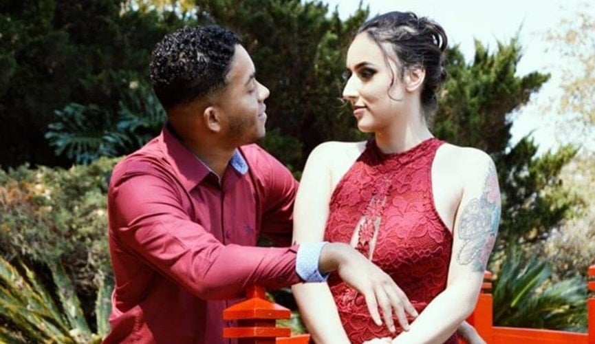 Casal com trajes vermelho em meio à vegetação