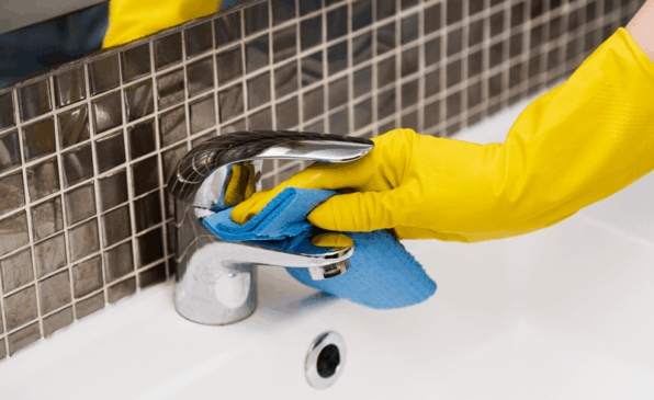 Pessoa com luva de borracha limpa banheiro com esponja