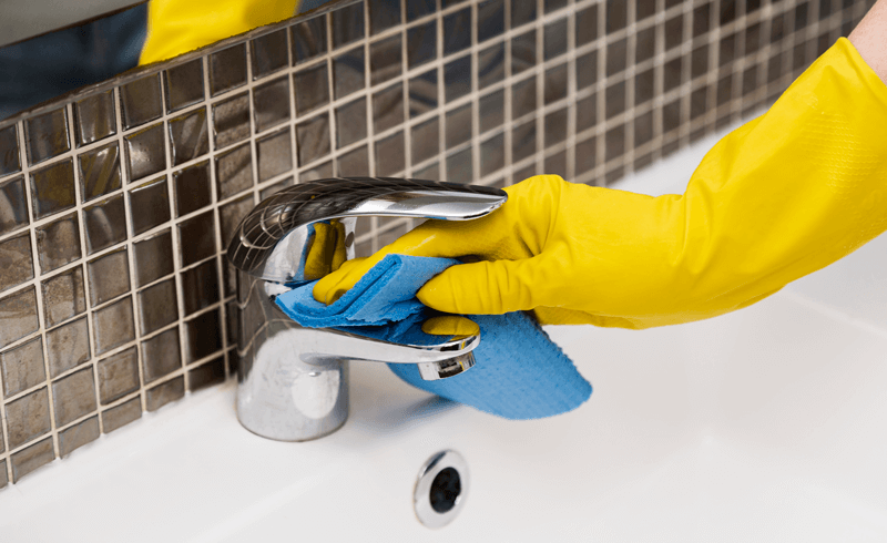 Pessoa com luva de borracha limpa banheiro com esponja