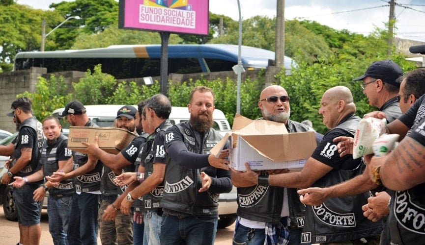 Integrantes de motoclube descarregando alimentos