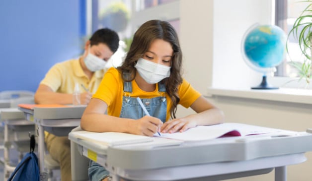 Crianças estudando com máscara