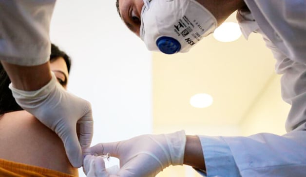 Mulher é vacinada por profissional da saúde