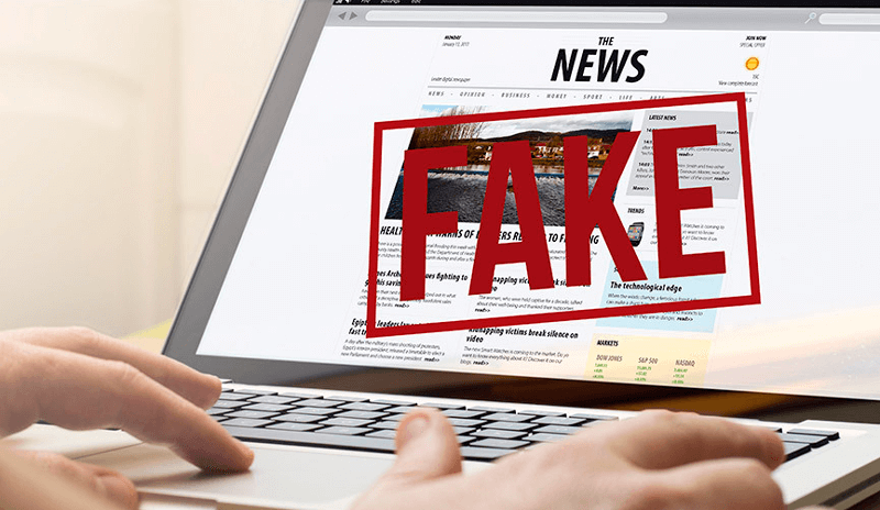 Computador aberto em site de notícias com carimbo fake sobre a tela