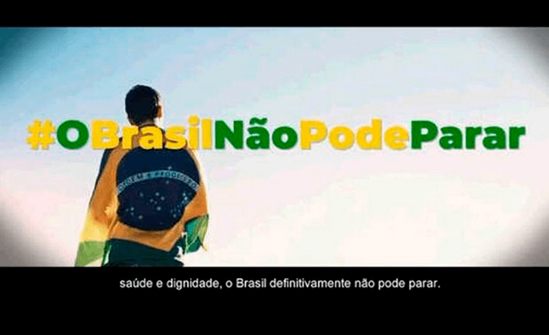 Homem com bandeira do Brasil nas costas e escritos: #OBrasilNãoPodeParar