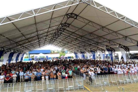 Público lota estrutura coberta na Praça CEU durante celebração dos 60 anos de Várzea Paulista, com autoridades e famílias presentes.