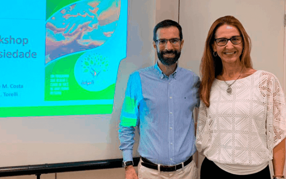 Dr. Carlos Henrique Costa e Luciana Roveri em frente a telão