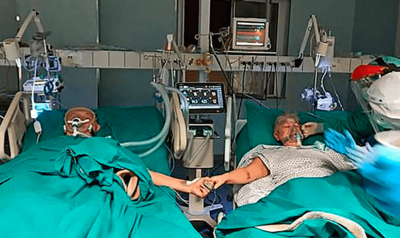 Casal de mãos dadas em leito da CTI