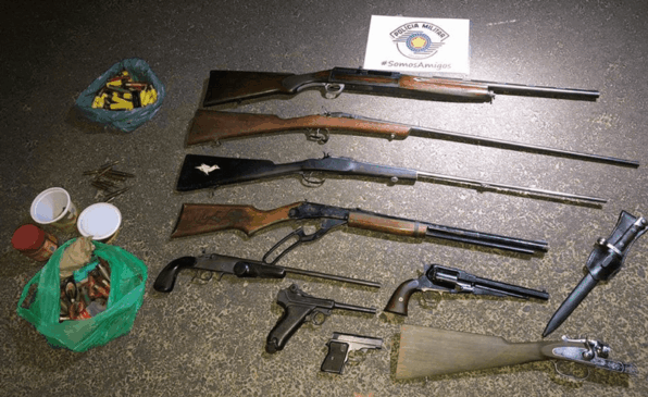 Armas de fogo e munição organizadas no chão