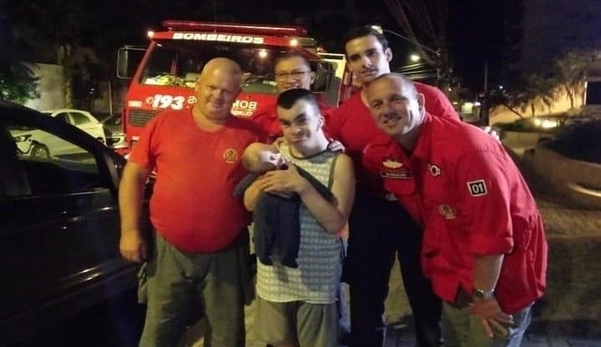 Foto de bombeiros com rapaz e boneco
