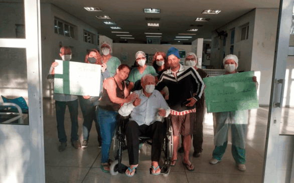 Idoso na cadeira de rodas ao lado de equipe médica