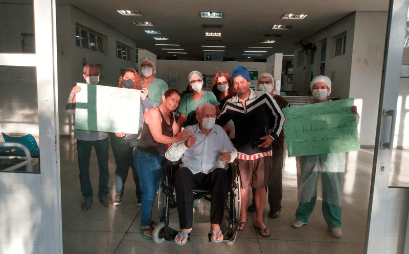 Idoso na cadeira de rodas ao lado de equipe médica