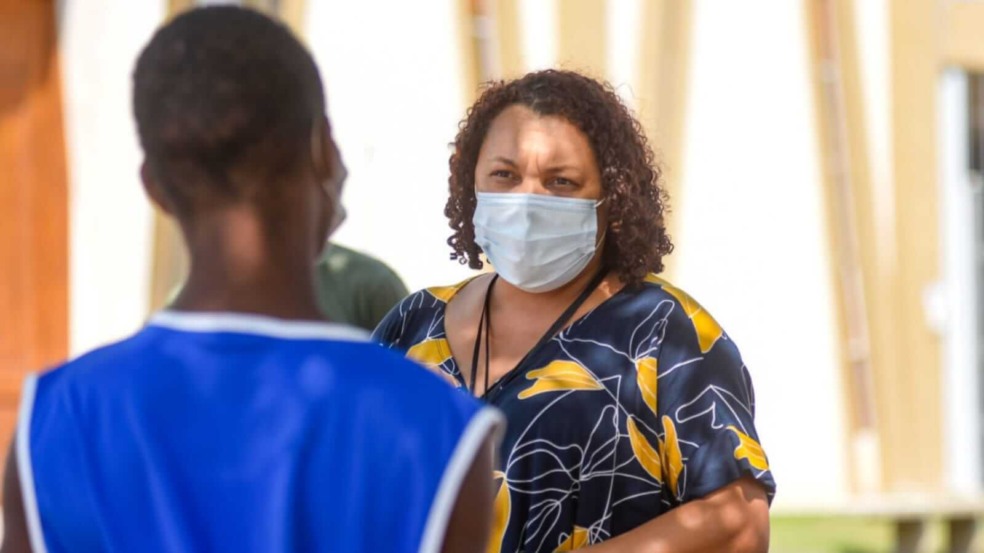 Mulher de máscara conversando com homem de costas