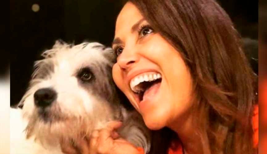 mulher sorrindo abraçando cão de estimação