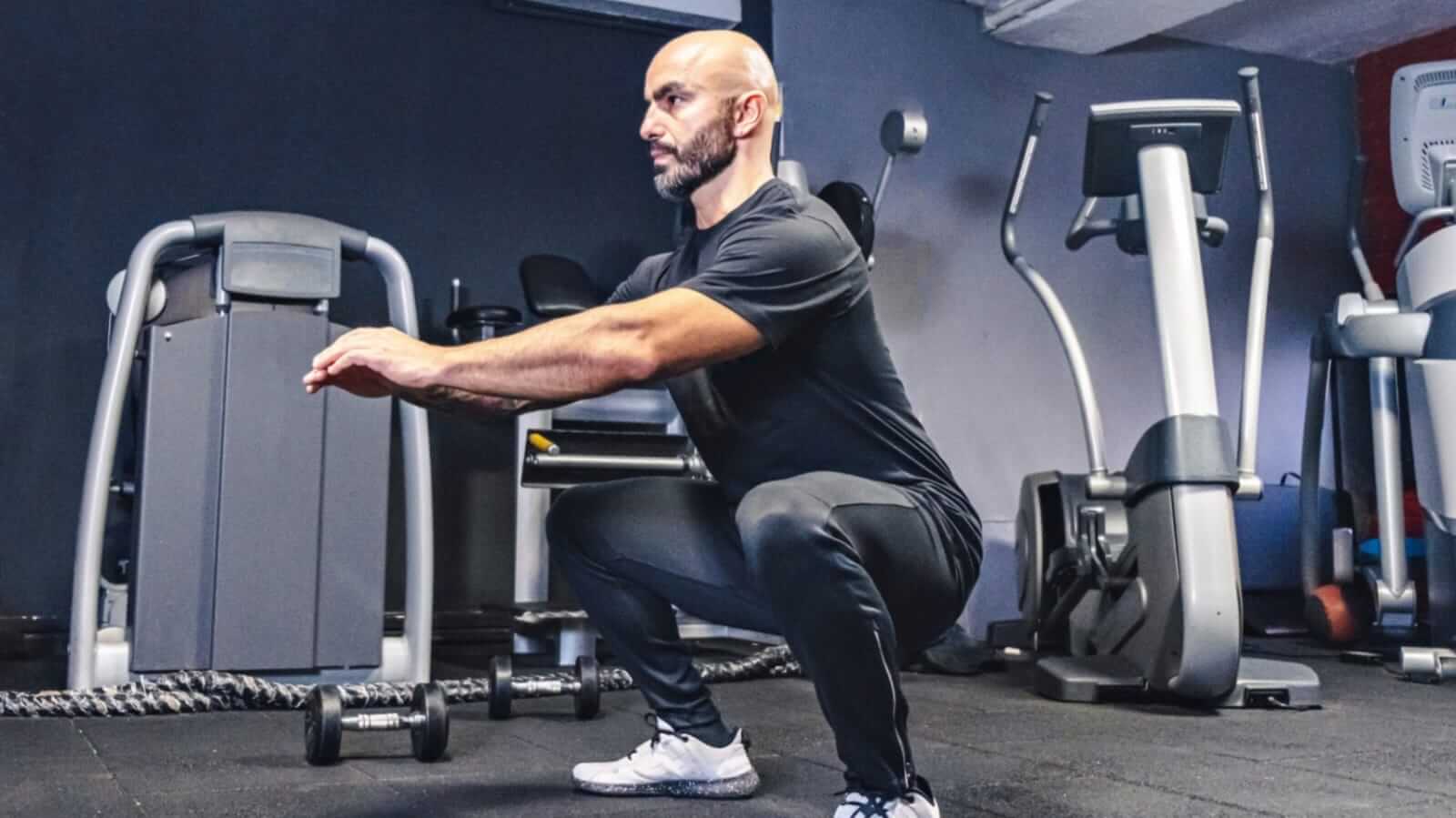 Homem fazendo treino de pernas com agachamento