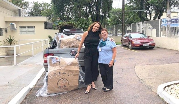 Foto de mulheres abraçadas ao lado de cadeiras de rodas encaixotadas