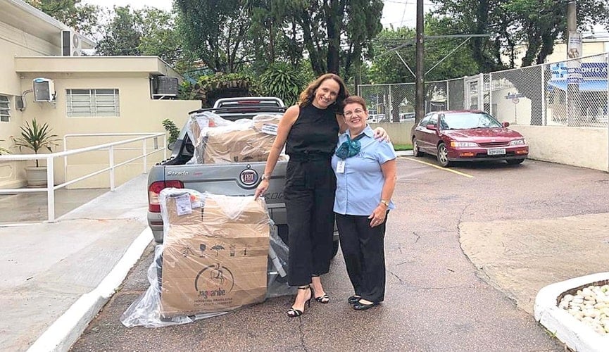 Foto de mulheres abraçadas ao lado de cadeiras de rodas encaixotadas