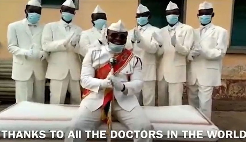 grupo de pessoas vestidas de branco ao lado de caixão