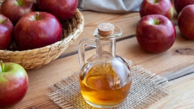 Frasco de vinagre com maçãs ao redor